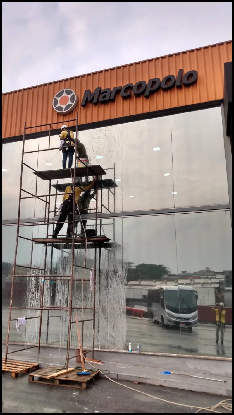 Equipe lavando os vidros de uma fachada com água e produtos de limpeza